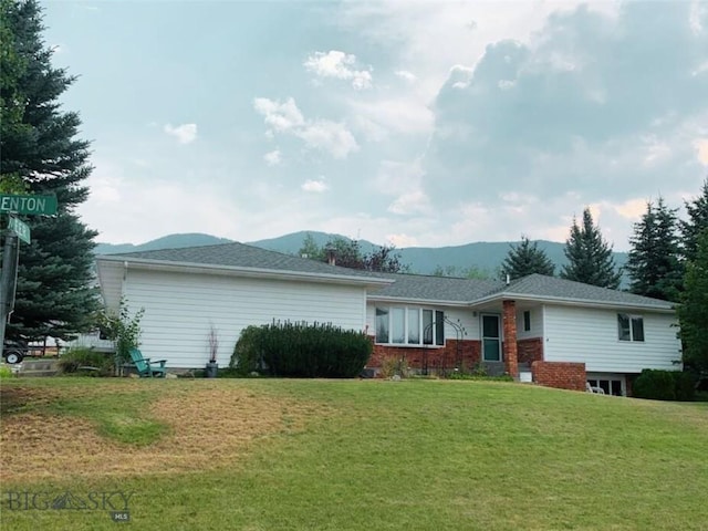 back of property featuring a mountain view and a lawn