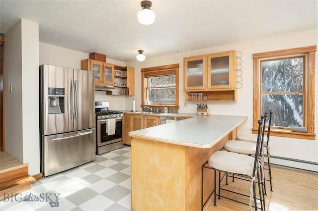 kitchen with a breakfast bar, appliances with stainless steel finishes, kitchen peninsula, and sink