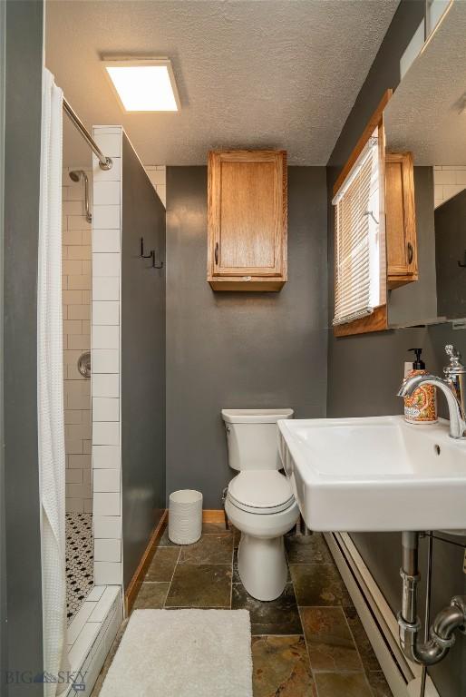 bathroom with a shower with curtain, toilet, sink, and a textured ceiling