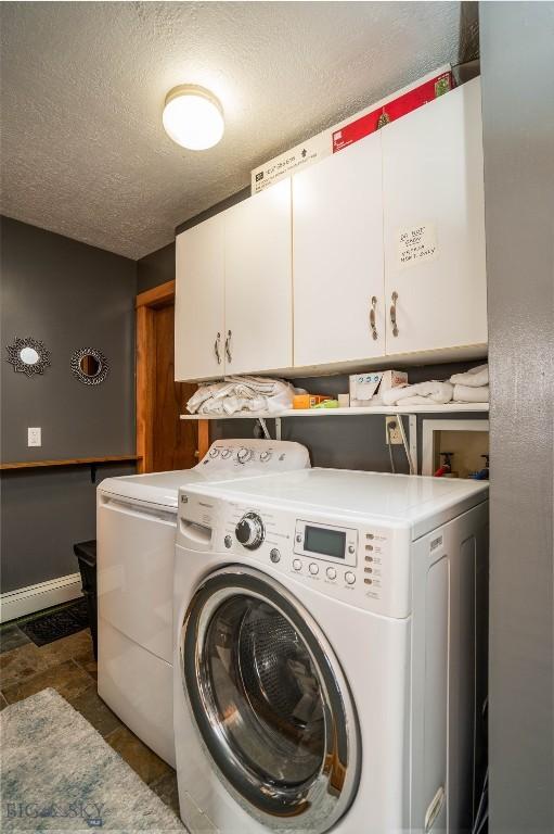 washroom featuring cabinets, washing machine and clothes dryer, and a textured ceiling