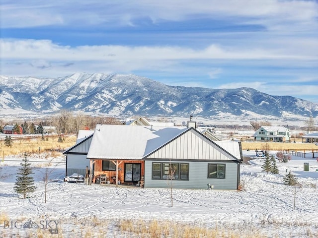 snow covered back of property featuring a mountain view