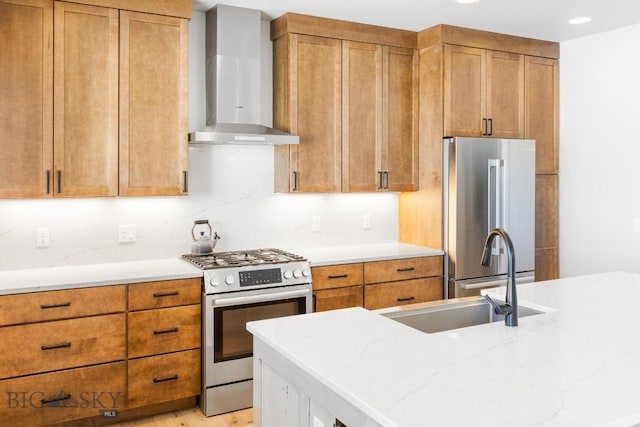 kitchen featuring wall chimney exhaust hood, sink, light hardwood / wood-style flooring, stainless steel appliances, and light stone countertops