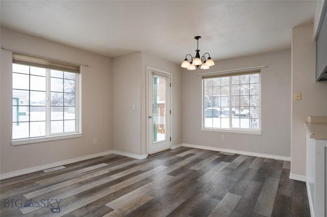 unfurnished dining area with dark hardwood / wood-style floors and a chandelier