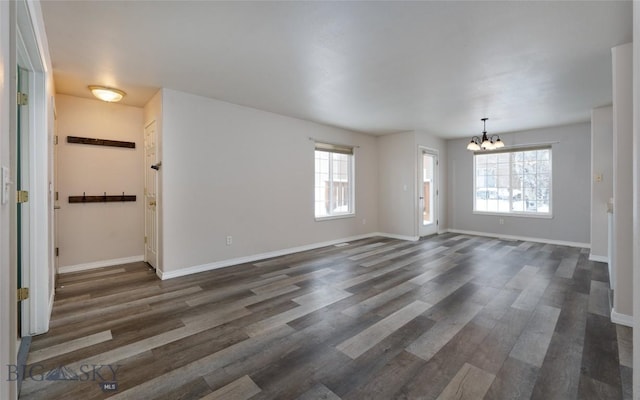 spare room featuring dark wood-type flooring, a chandelier, and a wealth of natural light