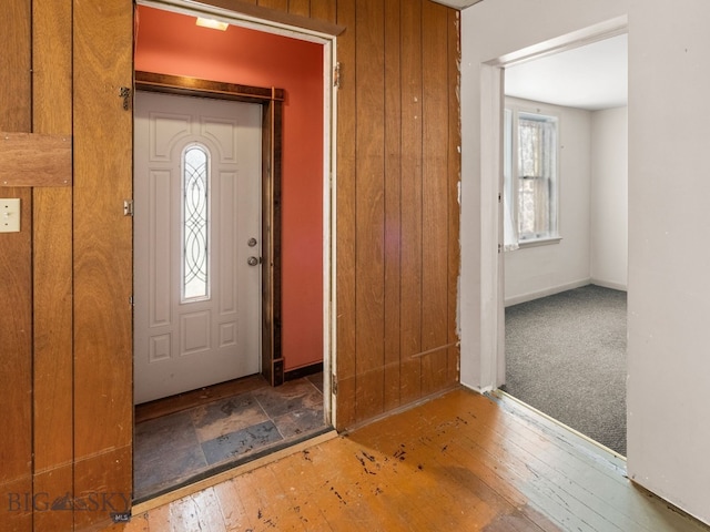 foyer entrance with wood-type flooring and wood walls