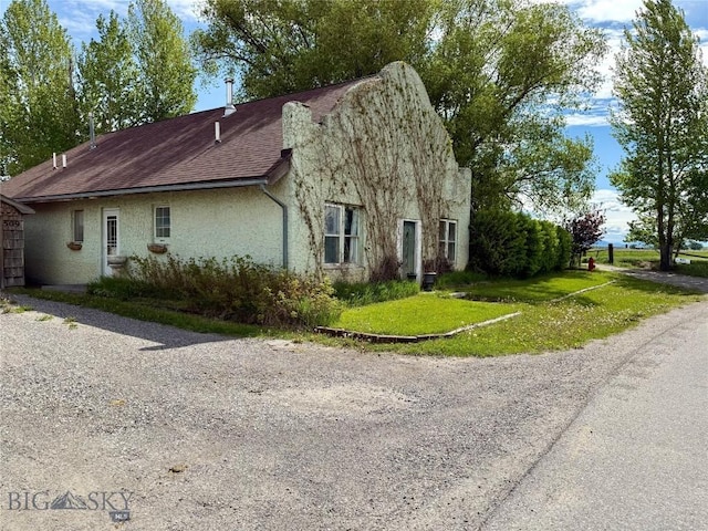 509 E Railroad N, Manhattan, MT 59741 - view of side of property with stucco siding, a lawn, and a shingled roof