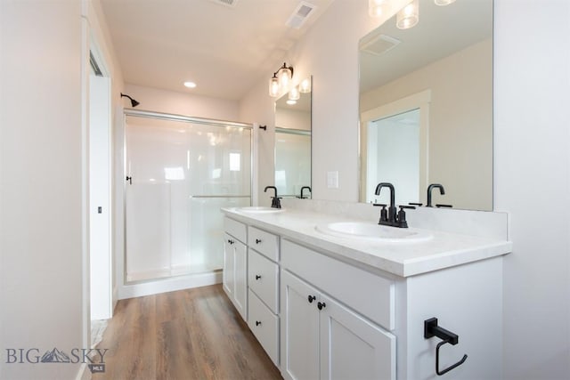 bathroom featuring wood-type flooring, a shower with shower door, and vanity