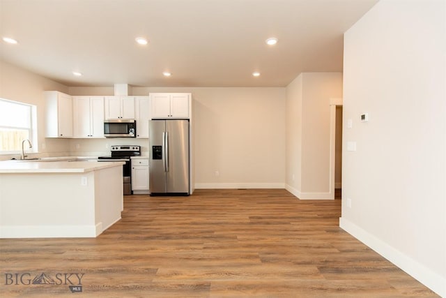 kitchen featuring appliances with stainless steel finishes, sink, white cabinets, and light hardwood / wood-style flooring