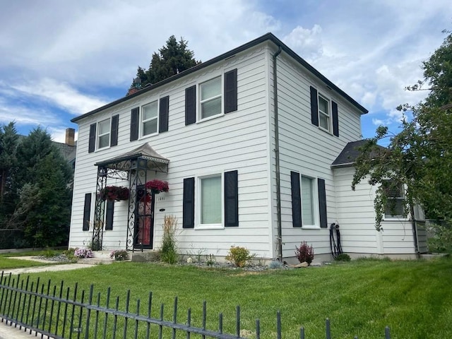 colonial home featuring a front lawn and fence