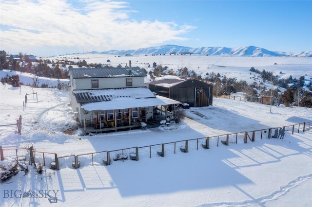 snow covered back of property with a mountain view