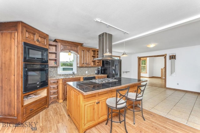 kitchen featuring a kitchen island, island range hood, tasteful backsplash, a breakfast bar area, and black appliances