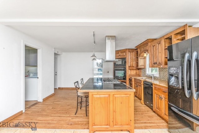 kitchen with island range hood, tasteful backsplash, a kitchen breakfast bar, a center island, and black appliances