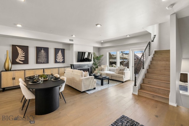 living room with a high end fireplace and hardwood / wood-style floors