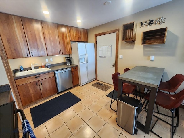 kitchen featuring dishwasher, sink, light tile patterned flooring, and white fridge with ice dispenser