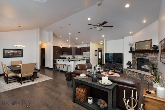 living room featuring a fireplace, ceiling fan with notable chandelier, dark wood-type flooring, and high vaulted ceiling