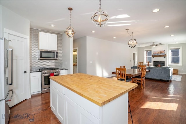 kitchen featuring wooden counters, white cabinetry, hanging light fixtures, high end appliances, and a kitchen island