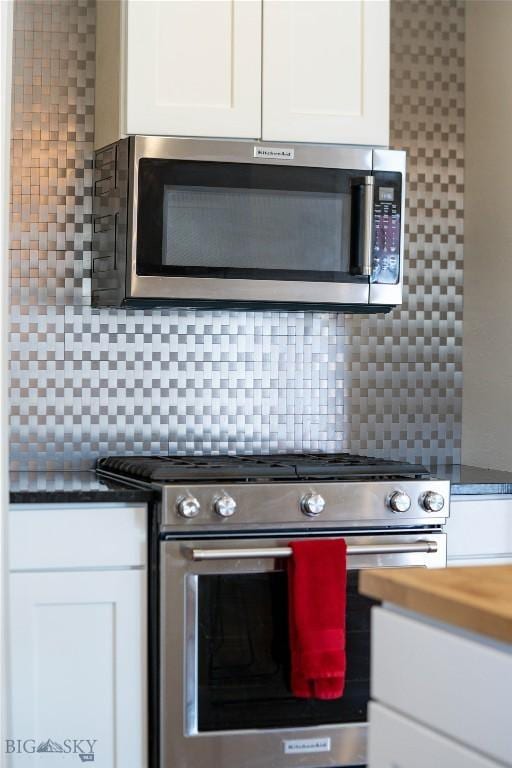 kitchen with stainless steel appliances, white cabinets, and backsplash