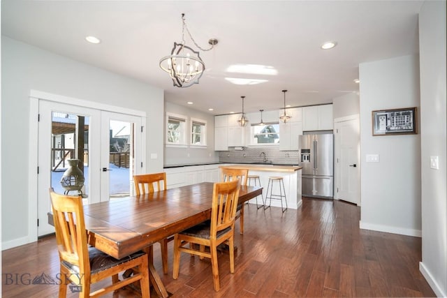 dining space featuring dark hardwood / wood-style floors, sink, an inviting chandelier, and french doors