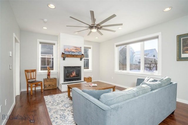 living room with dark hardwood / wood-style floors, ceiling fan, and a fireplace