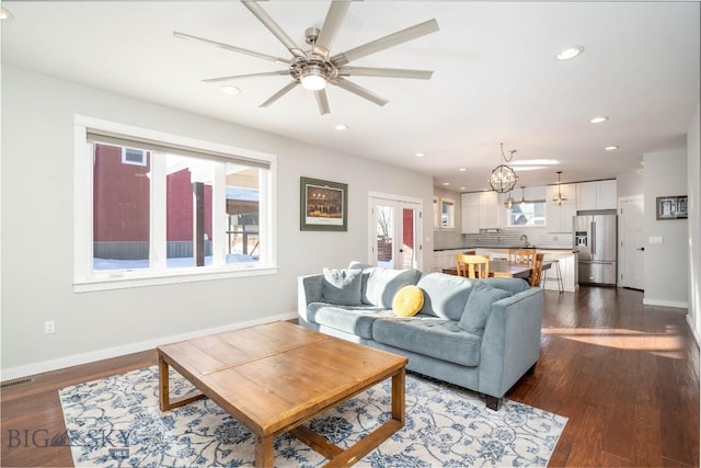 living room with sink, ceiling fan with notable chandelier, and dark wood-type flooring