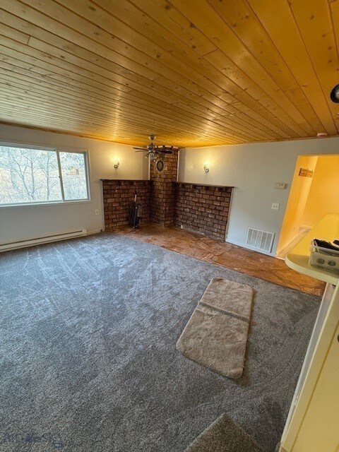 5042 US Highway 89 S, Livingston, MT 59047 - unfurnished living room with baseboard heating, carpet floors, wood ceiling, a brick fireplace, and ceiling fan