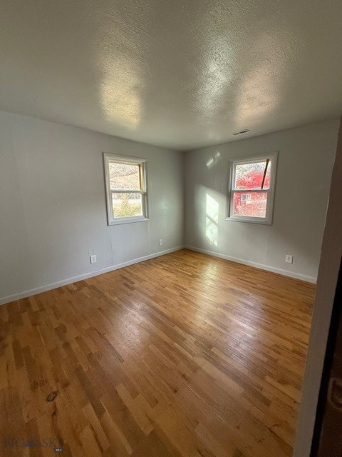 unfurnished room with hardwood / wood-style floors and a textured ceiling