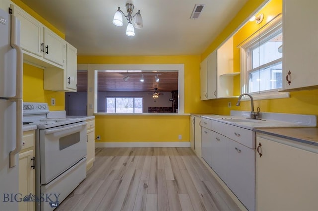 kitchen with white electric stove, sink, white cabinets, fridge, and light hardwood / wood-style flooring