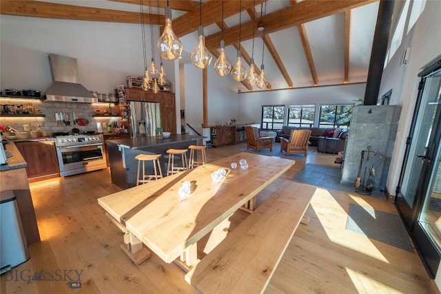 dining area with beam ceiling, high vaulted ceiling, and light wood-type flooring