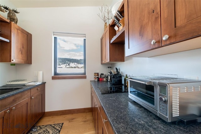 kitchen with black electric cooktop, dark stone counters, and hardwood / wood-style flooring