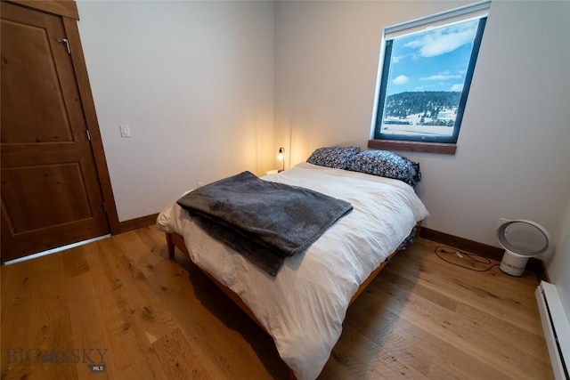 bedroom featuring a baseboard heating unit and light hardwood / wood-style floors