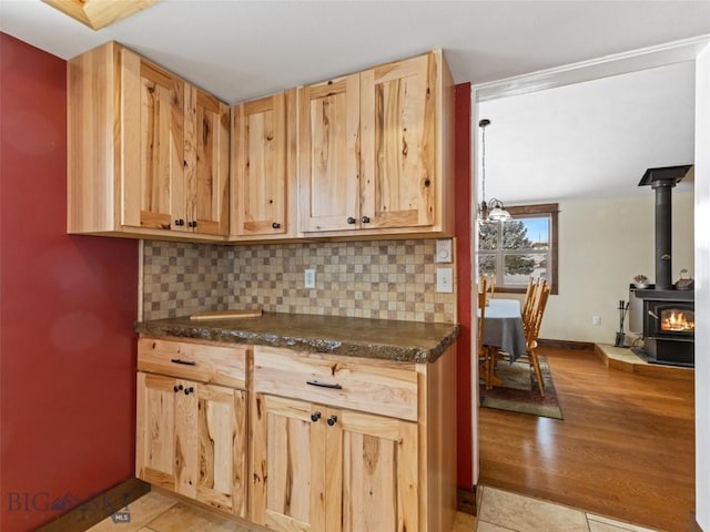 10 Fan Mountain Ct, Ennis, MT 59729 - kitchen with light brown cabinetry, backsplash, dark countertops, and a wood stove