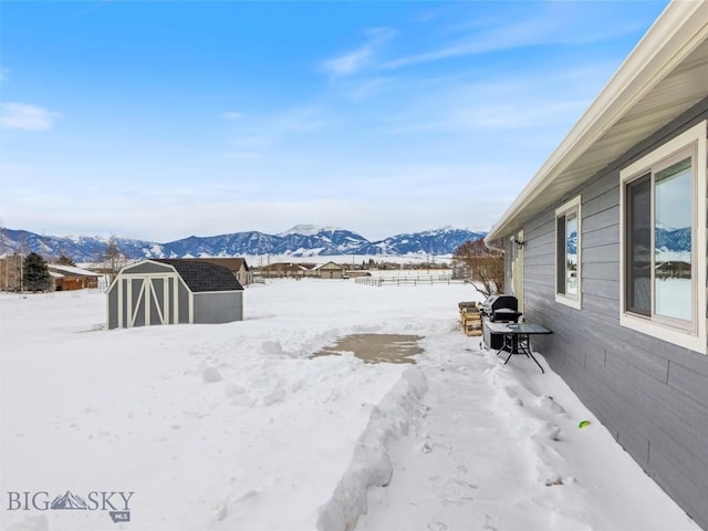 10 Fan Mountain Ct, Ennis, MT 59729 - yard layered in snow featuring an outdoor structure, a mountain view, a storage shed, and fence