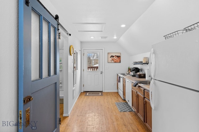 kitchen featuring lofted ceiling, light wood-type flooring, and white appliances