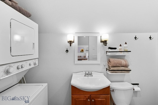 bathroom with vanity, toilet, and stacked washer / dryer