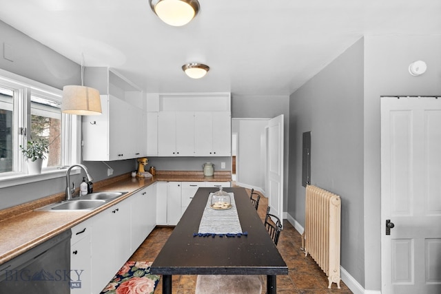 kitchen featuring radiator, sink, dishwasher, white cabinetry, and decorative light fixtures