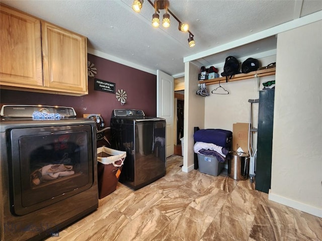 washroom featuring a textured ceiling, cabinets, and washer and clothes dryer