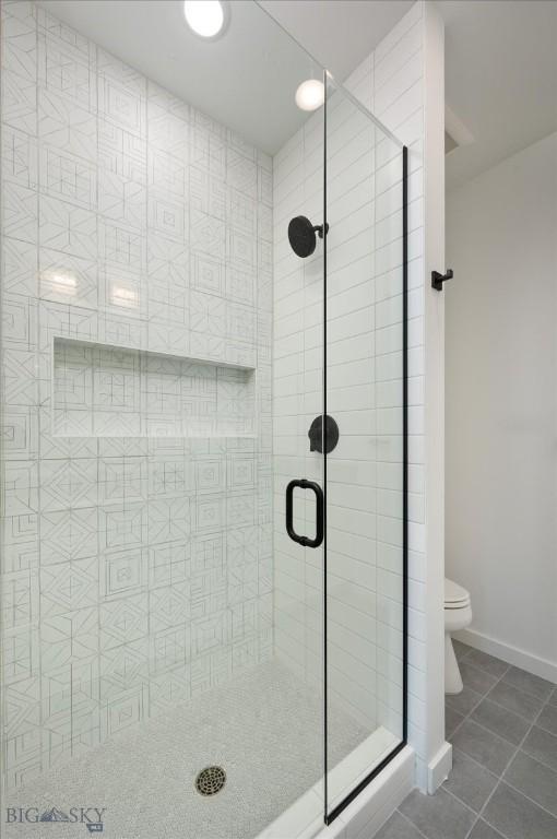 bathroom featuring tile patterned floors, toilet, and a shower with door