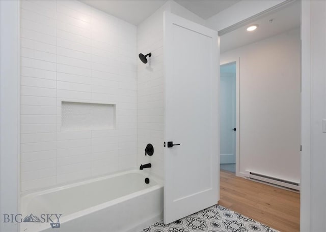 bathroom featuring tile patterned floors, tiled shower / bath, and baseboard heating