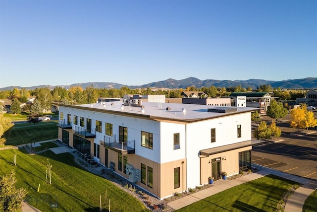 rear view of house with a mountain view and a yard