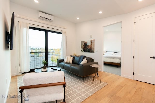 living room with a wall unit AC and light hardwood / wood-style floors