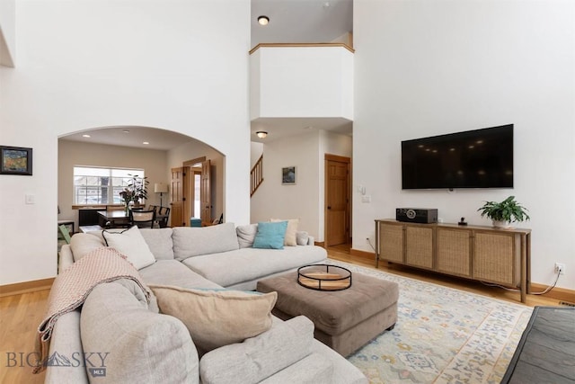 living room featuring light wood-type flooring and a high ceiling