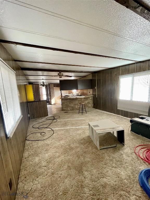 carpeted living area featuring wooden walls