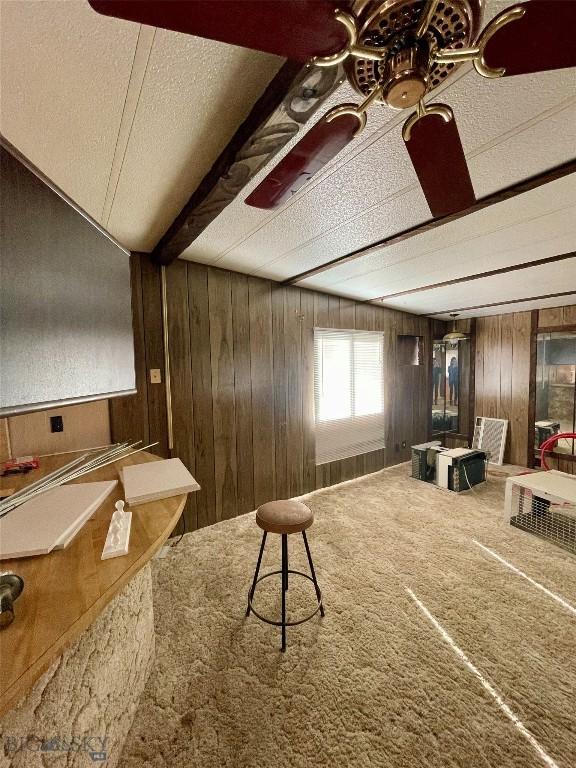 interior space featuring beamed ceiling, carpet flooring, and wooden walls