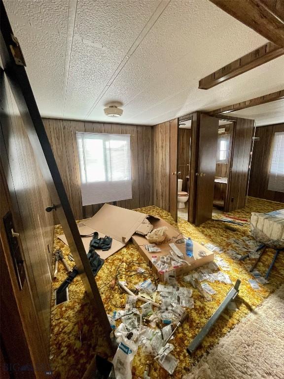 bedroom with wood walls, a textured ceiling, and ensuite bathroom