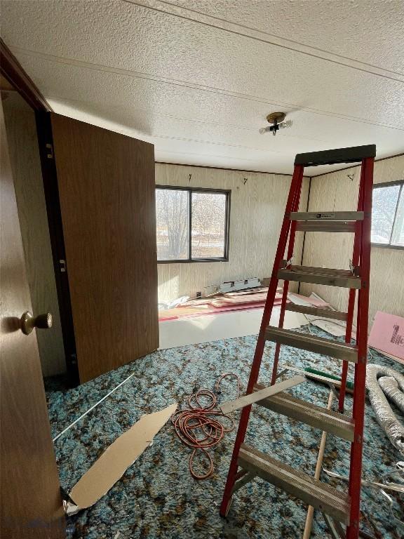 bedroom with wooden walls and a textured ceiling