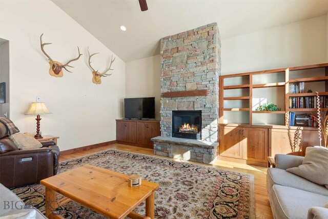 living room featuring a fireplace, vaulted ceiling, light hardwood / wood-style floors, and ceiling fan
