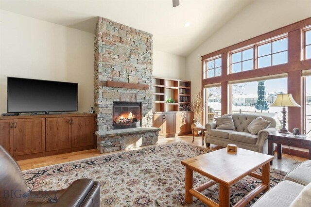 living room with a fireplace, high vaulted ceiling, and light wood-type flooring
