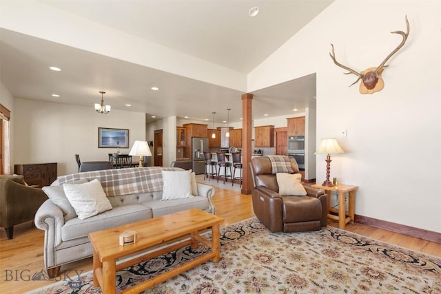 living room with vaulted ceiling, light hardwood / wood-style floors, decorative columns, and a chandelier