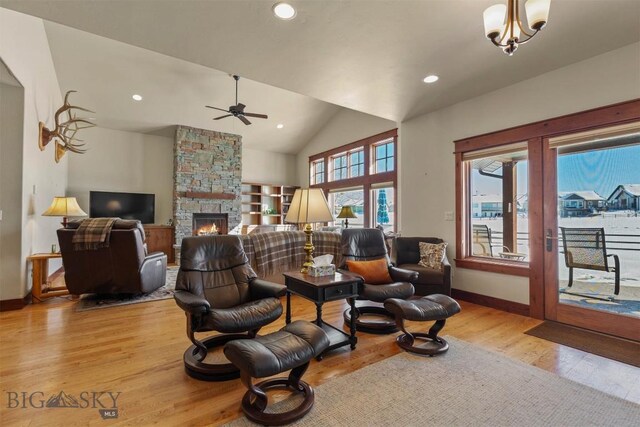 living room with vaulted ceiling, a fireplace, and light hardwood / wood-style floors