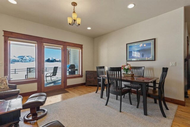 dining room with light wood-type flooring and a chandelier